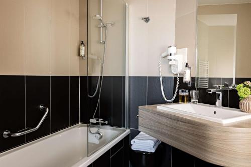 伊西莱穆利诺巴黎凡尔赛门贝斯特韦斯特酒店的浴室配有水槽、淋浴和浴缸。