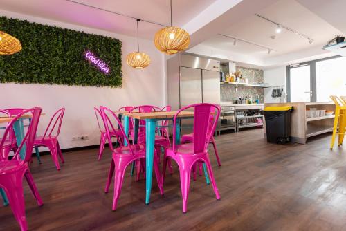 巴塞罗那Hostelle - Women only hostel Barcelona的配有桌子和粉红色椅子的房间