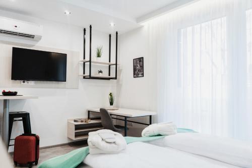 塞格德RIVA Szeged的白色的客房配有床、书桌和电视。