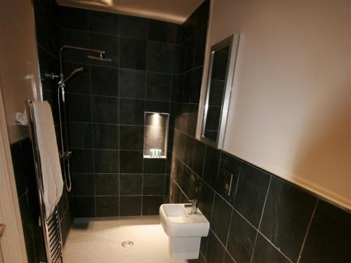 科尔切斯特Colchester Boutique Hotel的黑色瓷砖浴室设有卫生间和水槽