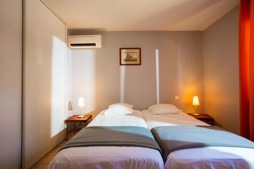 巴亚盖斯梅萨恩花园酒店的配有两盏灯的小房间内的两张床