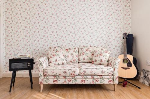 斯皮克George Harrison's Former 3Bed Home in Liverpool的带沙发和吉他的客厅