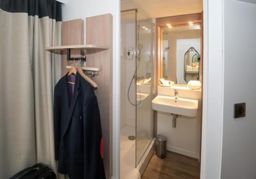 昂热Logis Hôtel Angers Sud的带淋浴的浴室和挂在架子上的外套