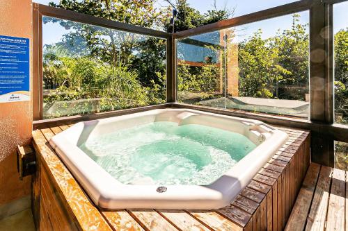 弗洛里亚诺波利斯Resort pé na areia - Suítes JBVTOP的木制甲板上的按摩浴缸,设有窗户