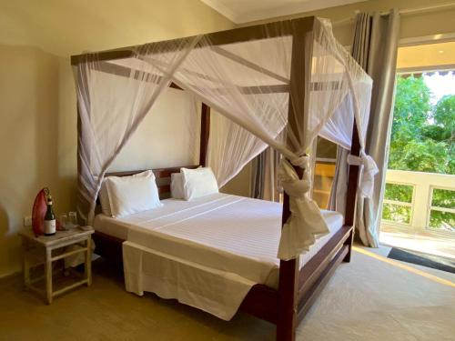 帕杰Paje Beach Apartments & Hotel的一间卧室设有天蓬床和窗户。