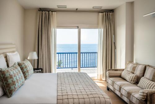 卡列罗港Villa Serenity的一间卧室配有一张床、一张沙发和一个大窗户