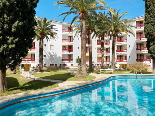萨洛Apartamentos Córcega Palmyra的一座楼前棕榈树游泳池