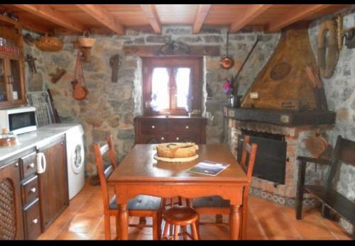 坎加斯-德奥尼斯Casa Rural El Cotu en Cangas de Onís的厨房配有木桌、椅子和壁炉