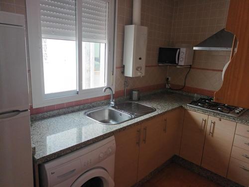 塞维利亚atico centrico nervion的一个带水槽和窗户的小厨房