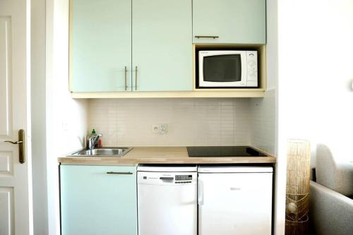格里莫Chez Adriana Studio Proche Mer avec Piscine的厨房配有白色橱柜、水槽和微波炉