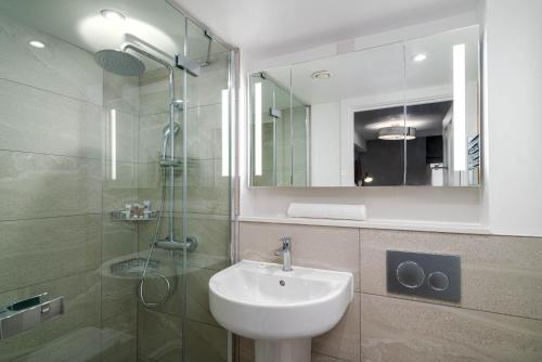 伦敦37 Doughty Street的浴室配有盥洗盆和带镜子的淋浴