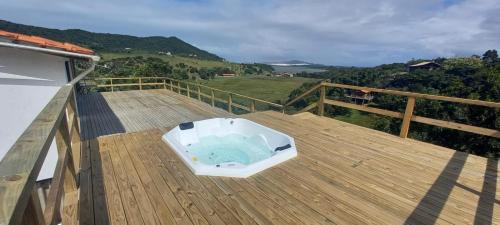 普腊亚罗萨Villa Santorini Praia do Rosa com piscina e jacuzzi的木制甲板上的浴缸