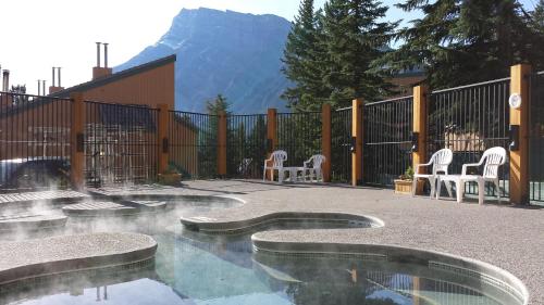 班夫花旗松小屋度假酒店的庭院设有带椅子的游泳池和山脉