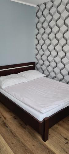 凯尔采Apartament Panoramiczna的铺有木地板的一张带白色床垫的床