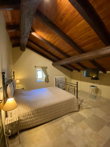马尔扎博托Tenuta Folesano Wine Estate 13th century的一间带一张大床的卧室,位于一个拥有木制天花板的房间