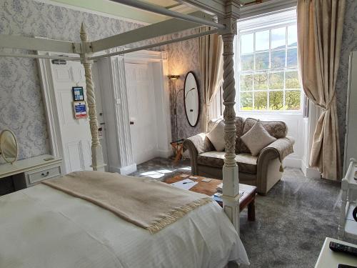 安布尔塞德Foxghyll Country House的一间卧室配有一张床、一张沙发和一个窗口
