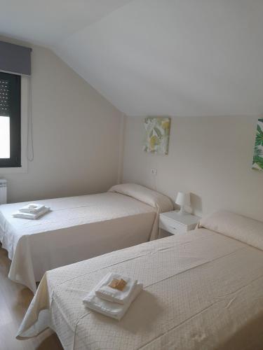 波尔托马林Sleeping portomarin 1的白色客房内的两张床和毛巾