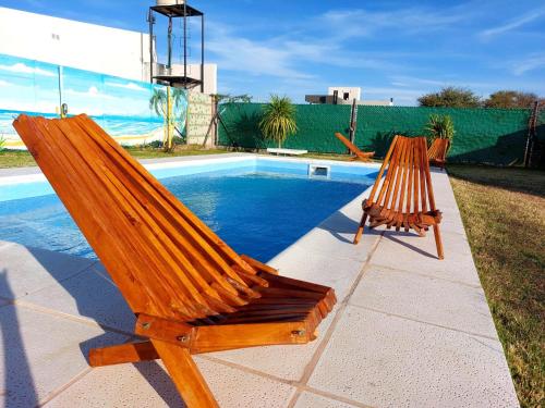 圣罗莎Cabaña Sarita的两把木椅,坐在游泳池旁