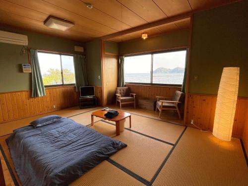 Kaiyo大砂荘 OZUNA CAMP and LODGE的卧室配有床、桌子和窗户。