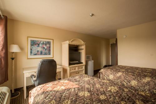 埃洛拉小镇旅馆的酒店客房设有两张床、一张桌子和一台电视。