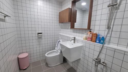 丹阳Jungle guesthouse的白色瓷砖浴室设有卫生间和水槽