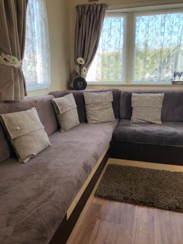 伯克顿Norfolk Lavender Caravan - Sleeps 4 - WiFi and Sky TV Included的客厅设有一张大沙发,配有窗户