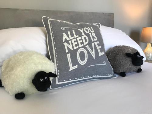 卡迪夫Inn Cardiff的两只塞满了毛的羊正坐在床上,床上有枕头
