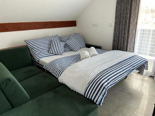 诺瓦佩奇Apartmán D5 Nová Pec的绿沙发上带条纹枕头的床