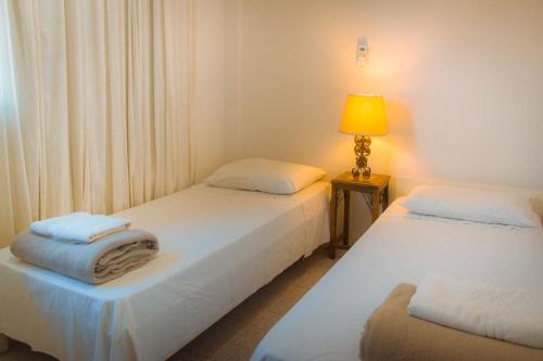 乌鲁瓜亚纳Hotel Solar dos Tchuccos的配有2张床的带灯和椅子的房间
