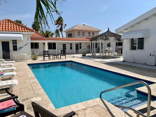 棕榈滩屠卡西塔阿鲁巴度假屋的一个带椅子的游泳池以及一座房子