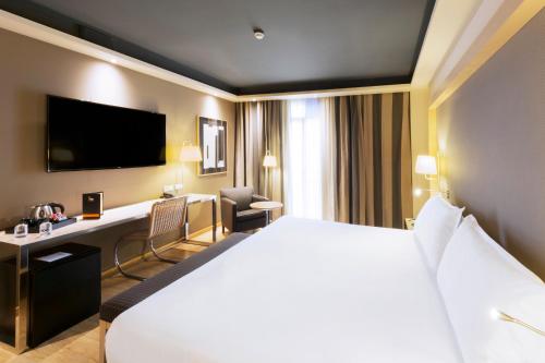 巴塞罗那爵士酒店的酒店客房设有一张白色大床和一张书桌