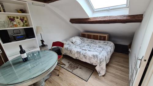 巴黎Appartement Cœur de Paris avec vue sur les toits的一间小卧室,配有一张床和一张玻璃桌