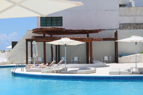 坎昆Cyan Cancun Resort & Spa的游泳池配有椅子、遮阳伞和水