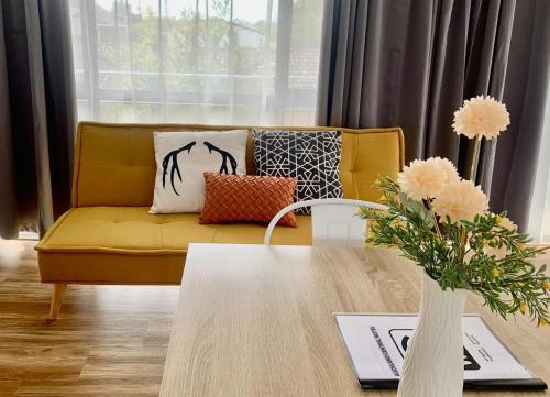 奥克兰Auckland Central Motel的客厅配有黄色的沙发和桌子