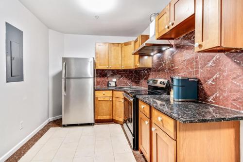 费城New and Cozy 1BD Apt in the heart of Philly!的厨房配有木制橱柜和不锈钢冰箱。