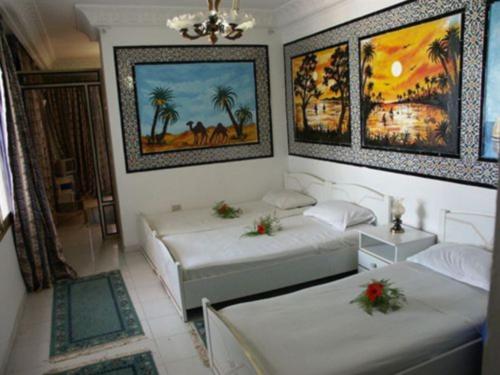 哈马马特汉密尔顿酒店的墙上挂有绘画的客房内的两张床