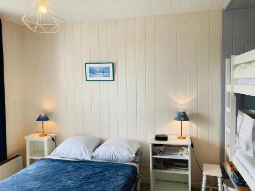 圣让-德蒙Maison des loriots, charme marin, plage à 100m的一间卧室配有一张床、两张桌子和两盏灯。