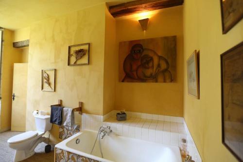 CorbonChambre jaune MANOIR DE LA VOVE Perche的带浴缸和卫生间的浴室以及绘画作品