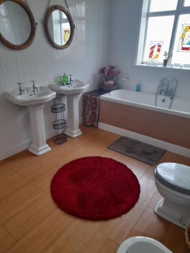 大雅茅斯Bastwick House B&B的浴室设有两个盥洗盆、一个浴缸和红色地毯。