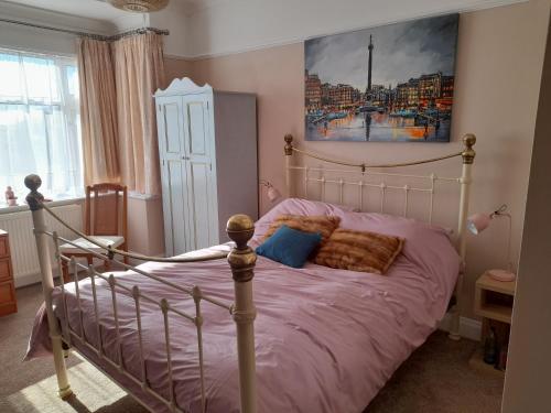 大雅茅斯Bastwick House B&B的一间卧室配有一张带紫色床单和绘画的床。