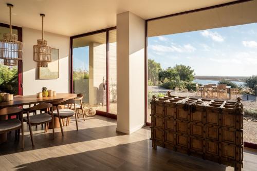 塔维拉Casa da Ria的厨房以及带桌子和大窗户的用餐室。