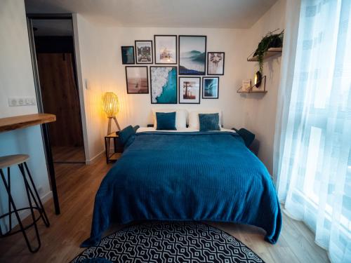 沙马列尔HESPERIE Thermes的卧室配有一张蓝色的床,墙上挂有图片