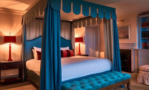 泰晤士河畔金斯顿The Mitre, Hampton Court的一间卧室配有一张带蓝色窗帘的天蓬床