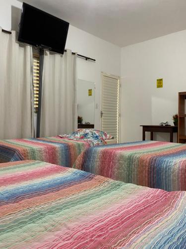 圣若昂-巴蒂斯塔-杜格罗里亚Chalés praia vermelha的配有平面电视的客房内的两张床