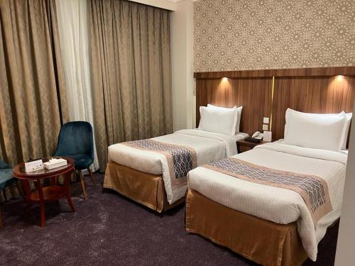 麦地那Saraya Harmony Hotel A的酒店客房,配有两张床、一张桌子和一把椅子