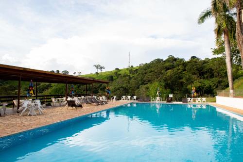 塞拉内格拉Hotel Fazenda Vale da Cachoeira的一座带椅子和树木的大型游泳池