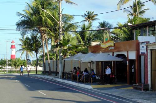 萨尔瓦多FAROL BEACH Apartamentos & Suítes的一群人坐在带灯塔的餐厅外面