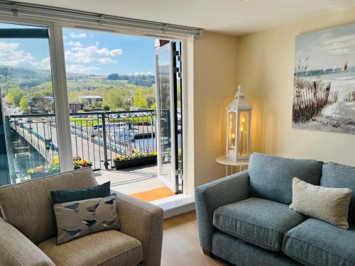 巴洛赫Riverside View Penthouse in Balloch, Loch Lomond的带沙发和大窗户的客厅
