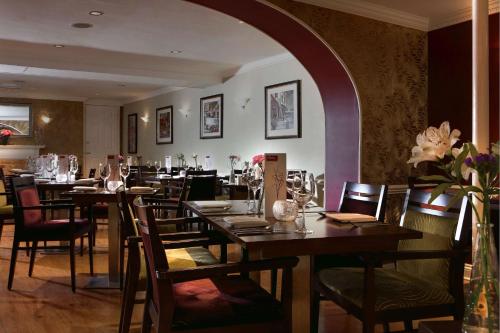 多切斯特Best Western Wessex Royale Hotel Dorchester的餐厅设有木桌和鲜花椅子