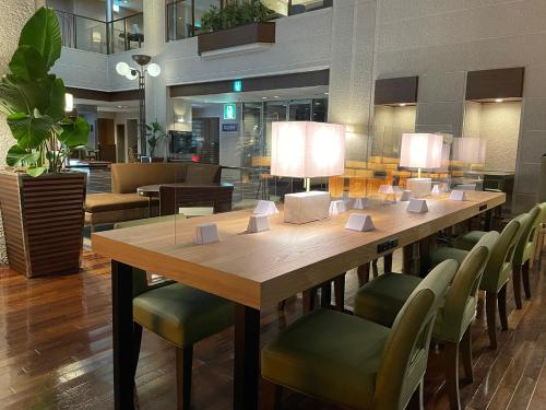 名古屋CYPRESS HOTEL Nagoya-eki Mae的一张带绿色椅子和灯的大木桌